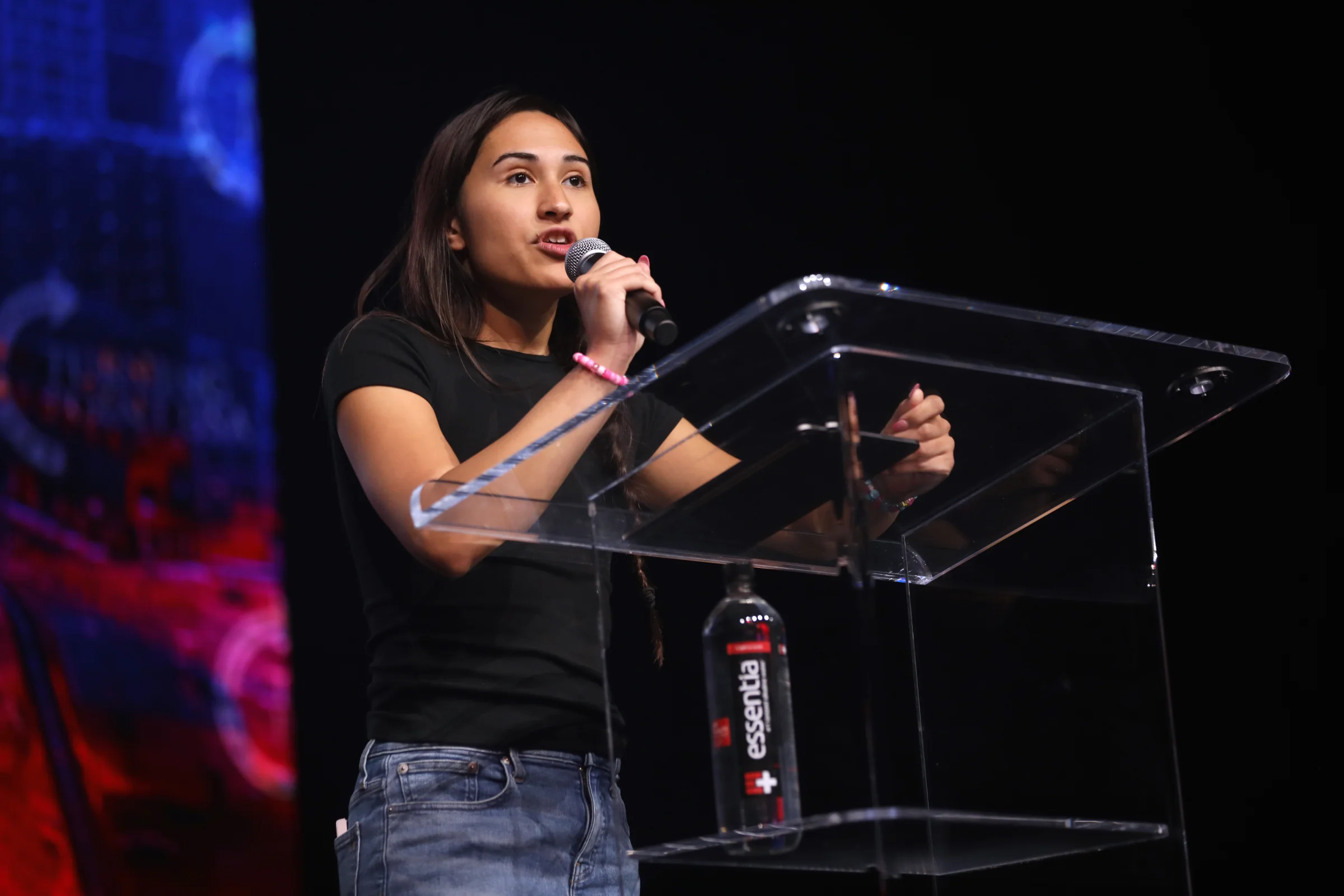 Chloe Cole speaking into a microphone from a clear podium